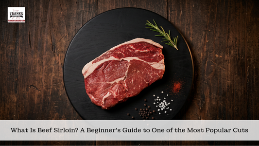 Raw beef sirloin steak on black slate plate with fresh rosemary, sea salt, and peppercorns on dark wood background, ready to cook.