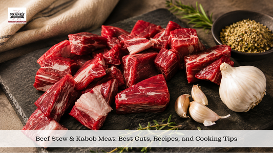 Cubed beef stew and kabob meat on dark slate with garlic, rosemary and peppercorns